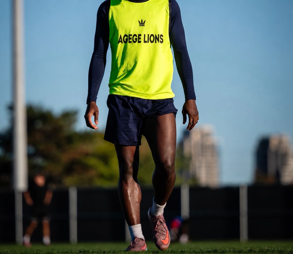 Agege Lions player in a neon bib walking onto the pitch